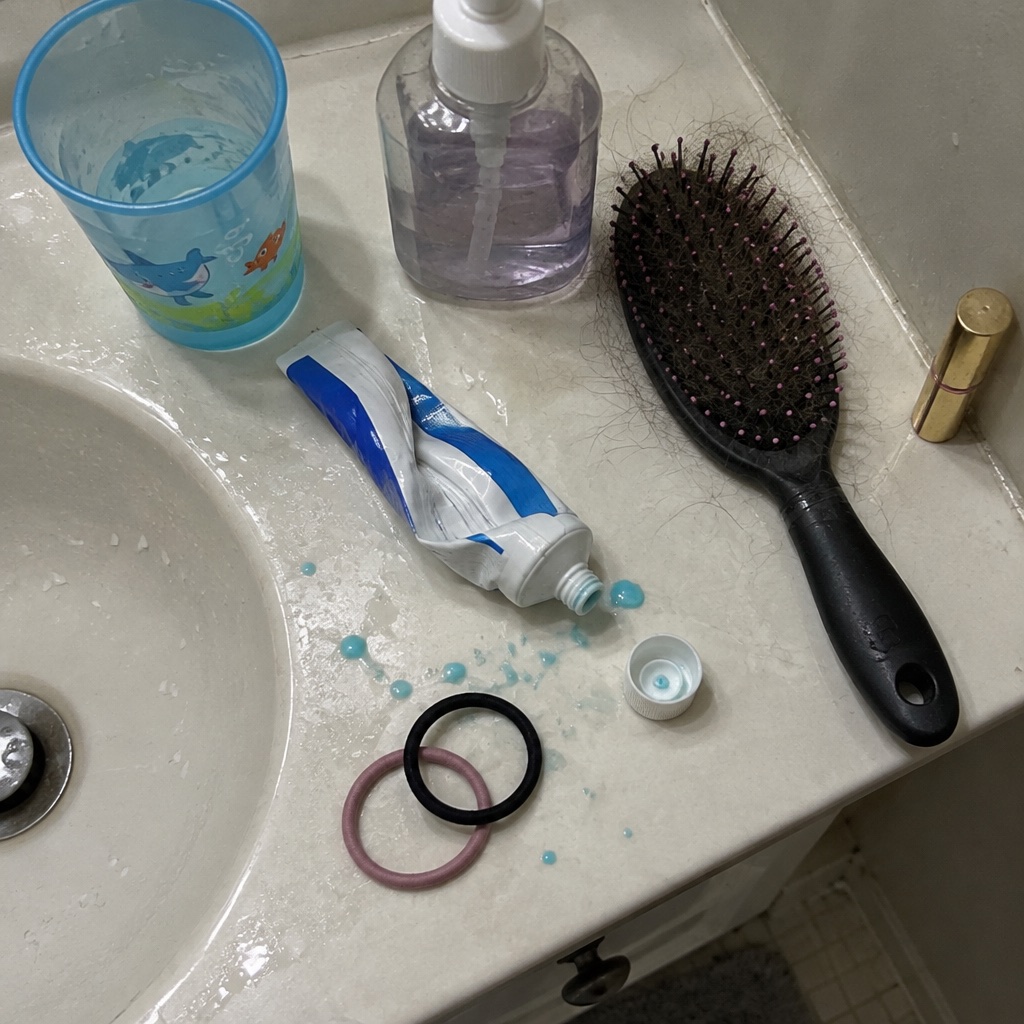 A cluttered family bathroom sink on a weekday morning